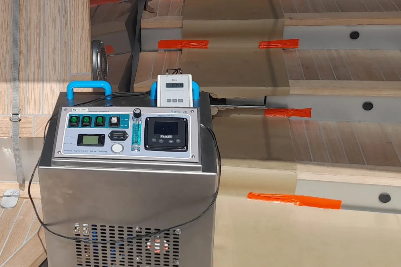Compact water dosing unit on a yacht aft deck, teak protected with covering