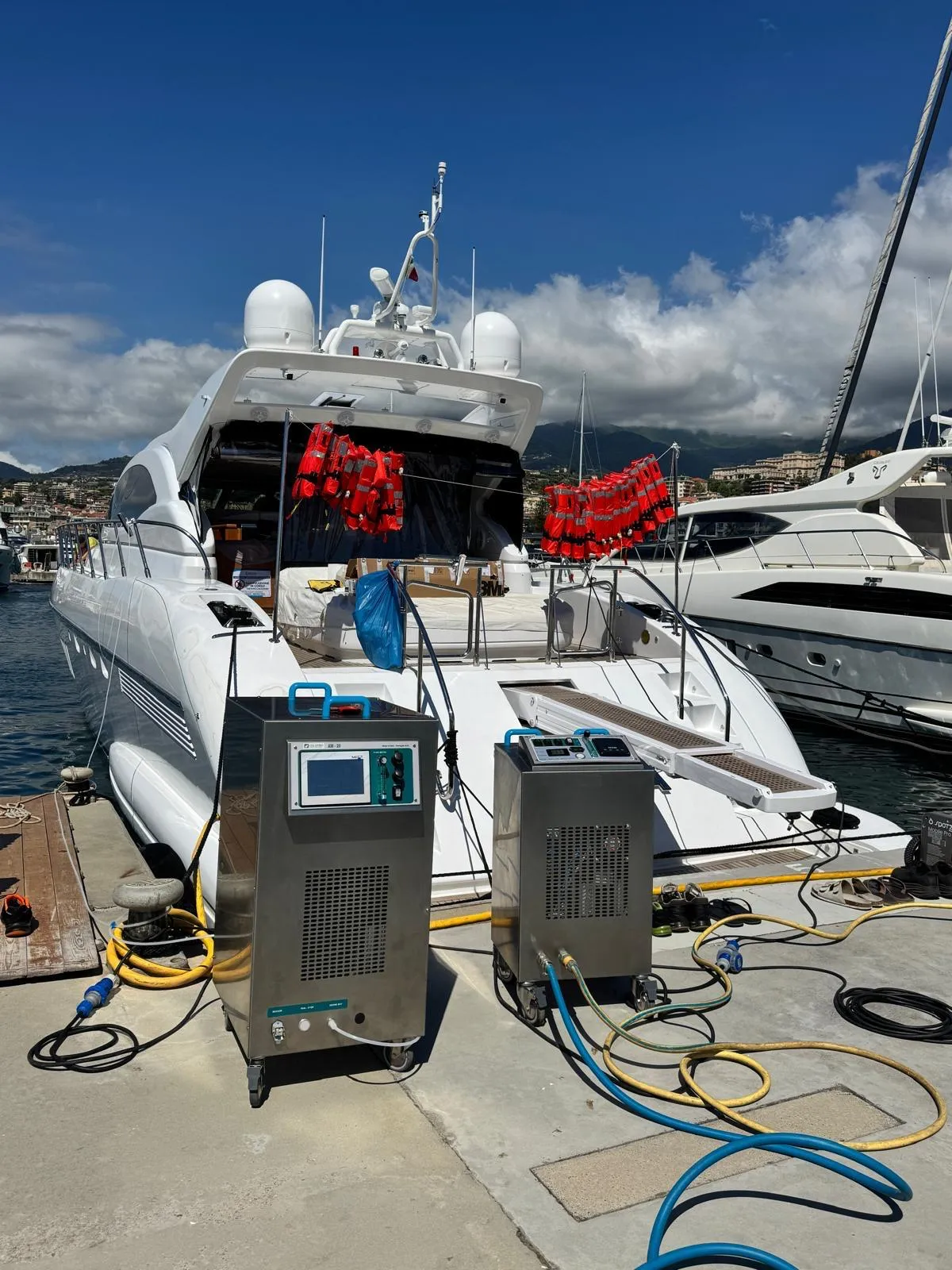 Two stainless-steel sanitization machines on the quay behind a motor yacht